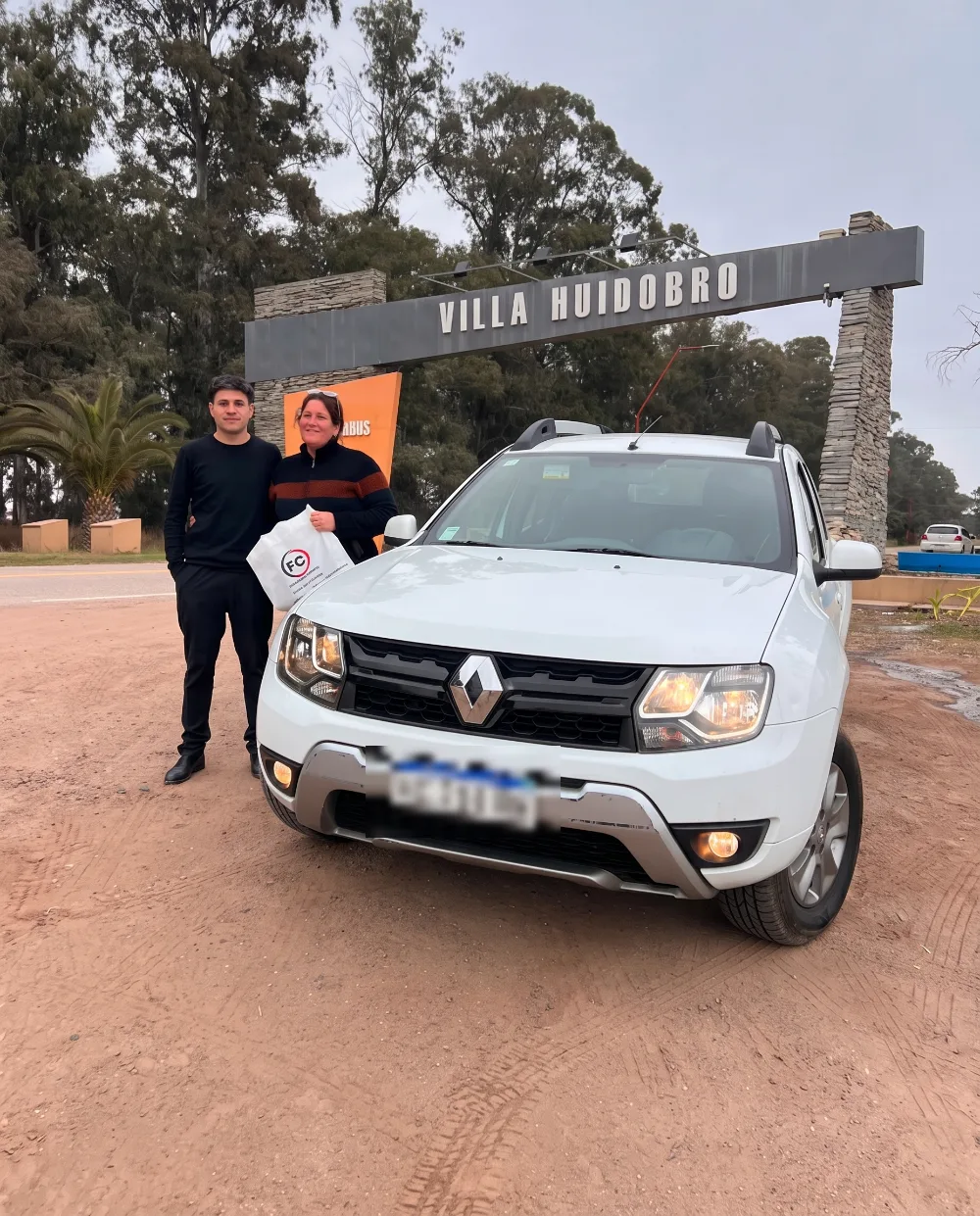 Entrega de un Renault Duster blanco en Villa Huidobro, Córdoba, junto al cartel de entrada a la localidad